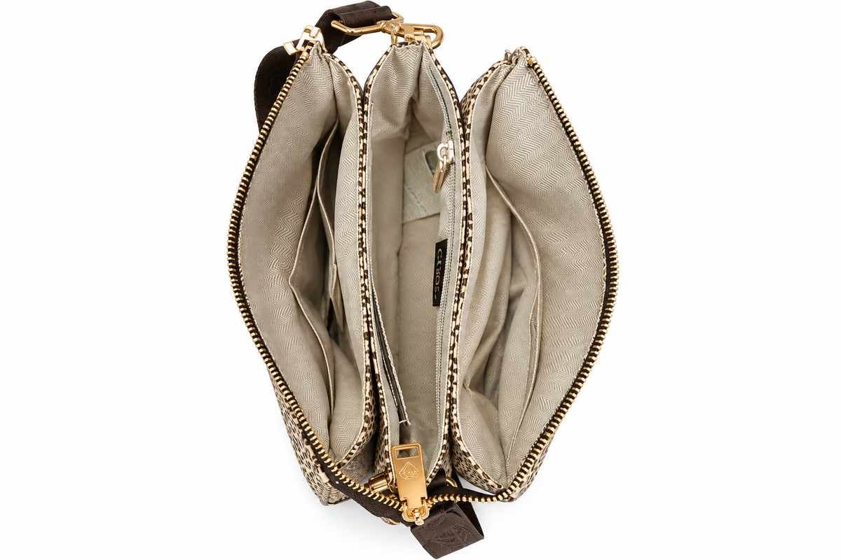 Interno della borsa Caleidos animalier aperta, con tre scomparti e fodera chiara, su sfondo bianco